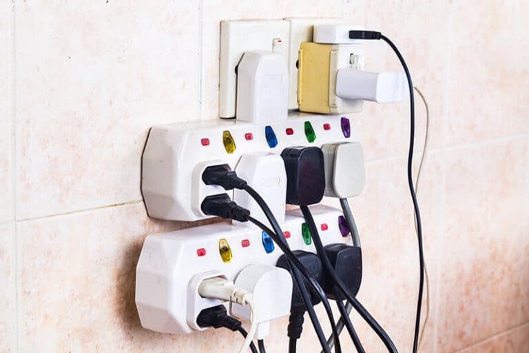 Overloaded electrical outlet with multiple plugs, highlighting the need for safe power usage in Cairns homes.
