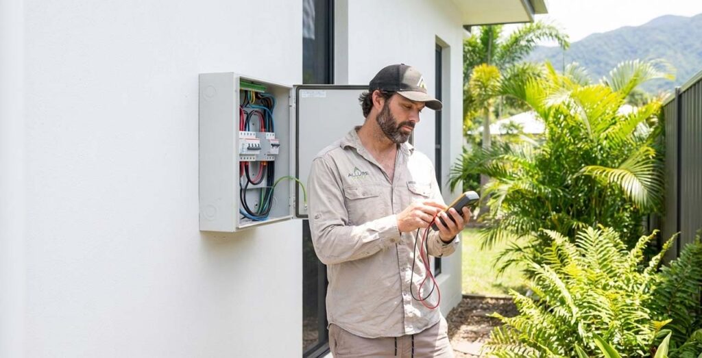 Electrician Cairns QLD working on an outdoor switchboard at a Cairns home, photographed in Ogilvy-style for Allure Energy.